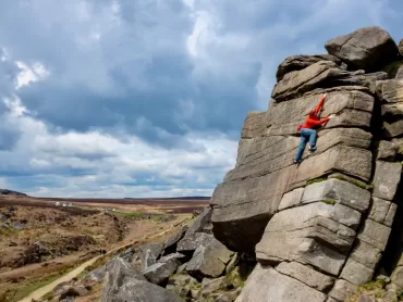 A man rock climbs on Burbage Edge in the Peak District.