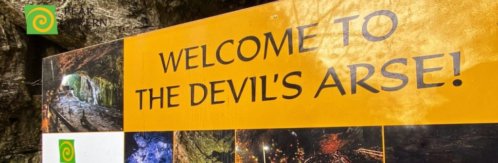 Devils arse welcome board sign at Peak Cavern.